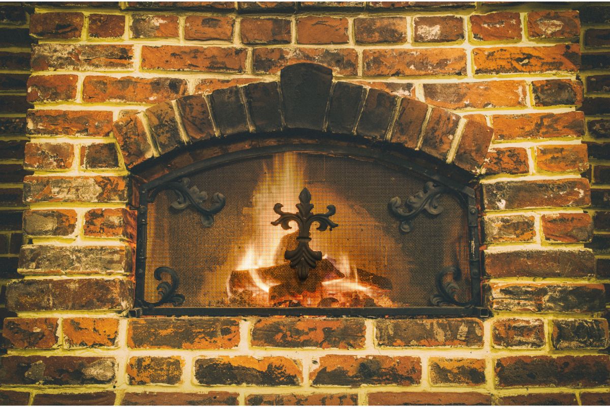 fireplace in brick wall with metal mesh screen