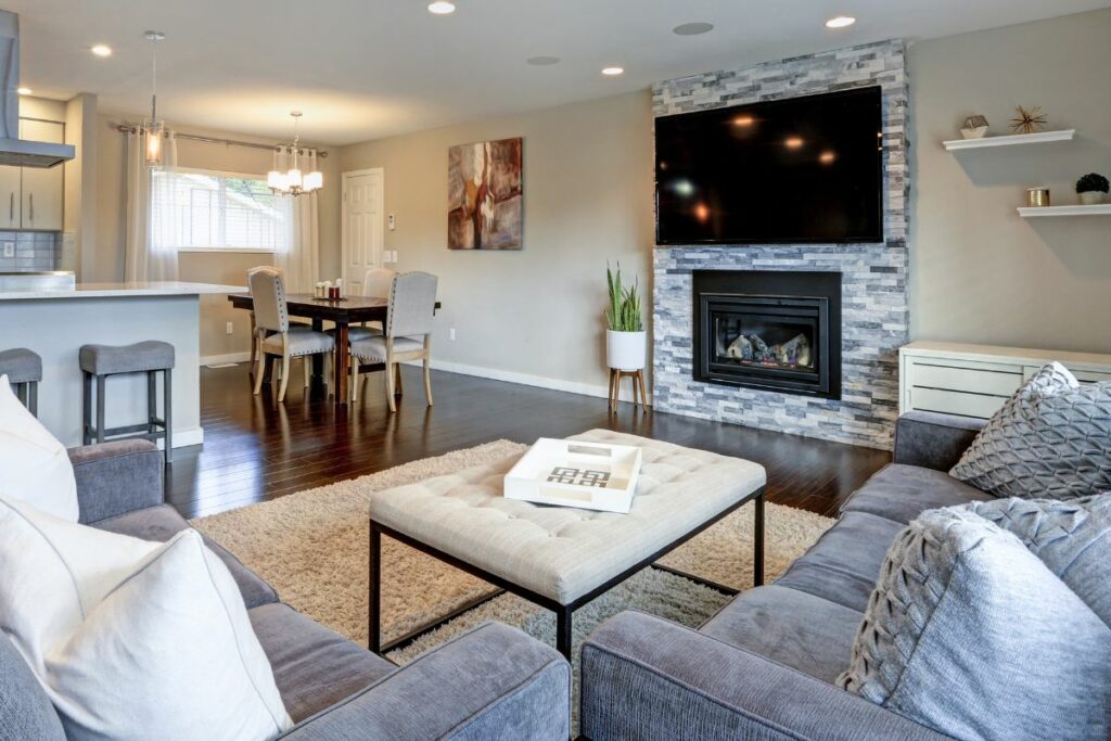 Fireplace under TV with grey coloured stone wall in living room
