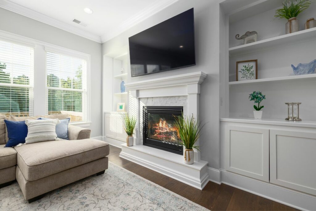 TV above fireplace in modern living room with rug and sofa.