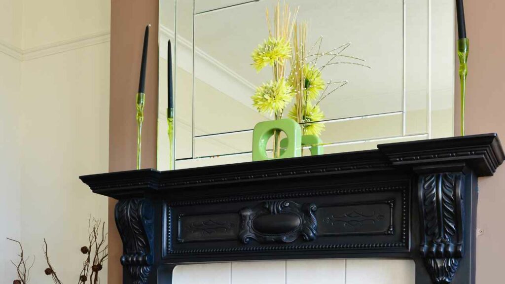 Black mantel. With flowers and candles on the mantel. Mirror above the mantel. 