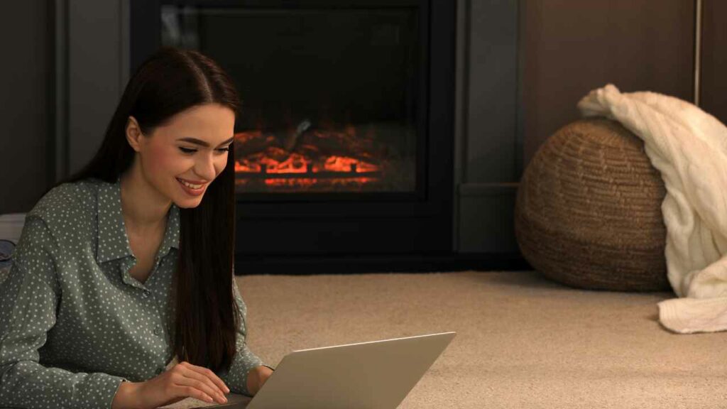 Elecrtric fireplace with woman in front on a laptop