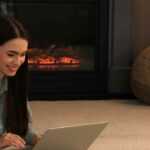 Elecrtric fireplace with woman in front on a laptop
