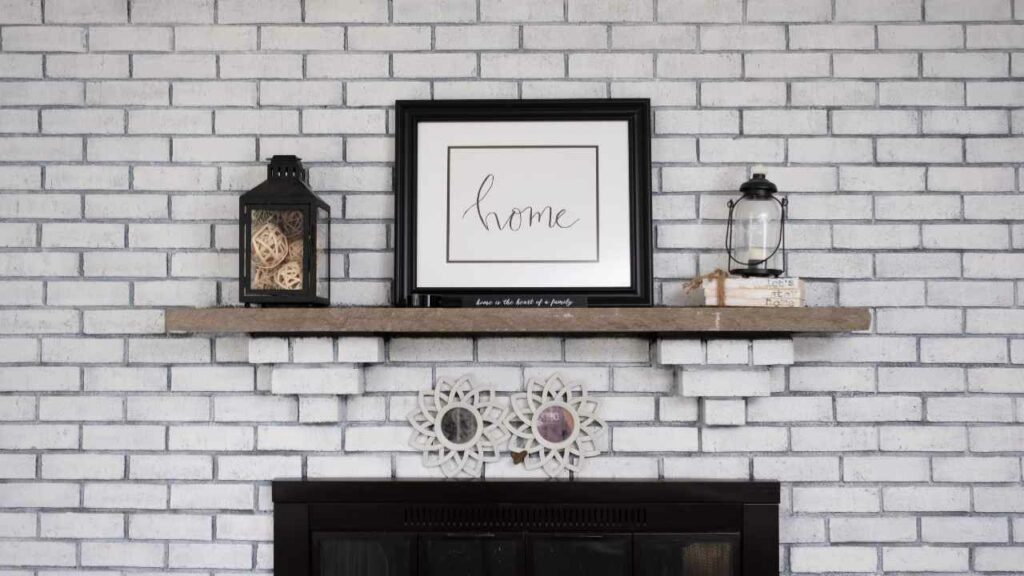 Floating wood mantel above electric fireplace. White washed walls. two candles and picture on the mantel.