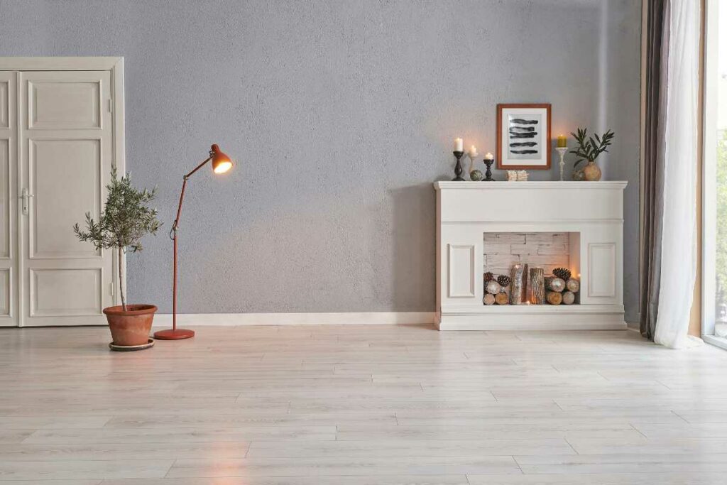 White washed fireplace in empty room with wood and candle decorations