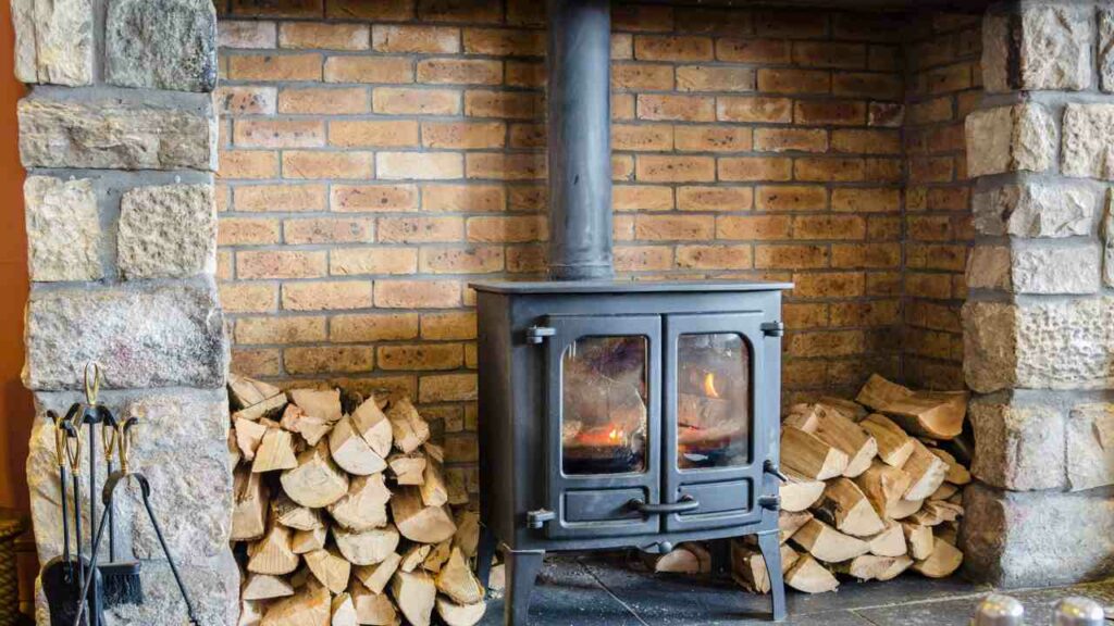 REed brick fireplace. Wood burning stove. Wood stacked either side.