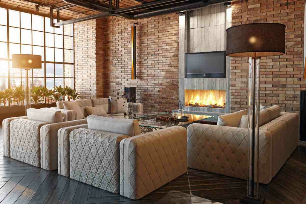 Fireplace in living room with sofa and TV above. Brick walls.