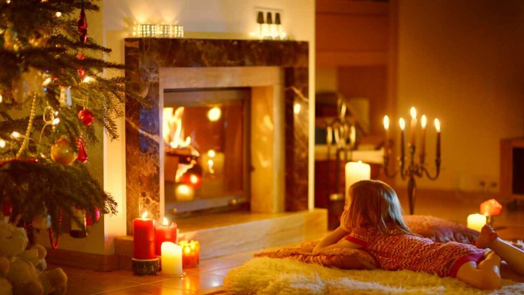 wood burning fireplace. fire burning. candles in front. candle stick to the right. cream rug with child.