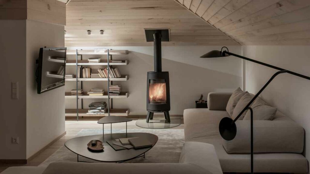 Modern wood burning fireplace with direct venting. Glass fronted fireplace with fire burning brightly. Wood walls and ceiling. 