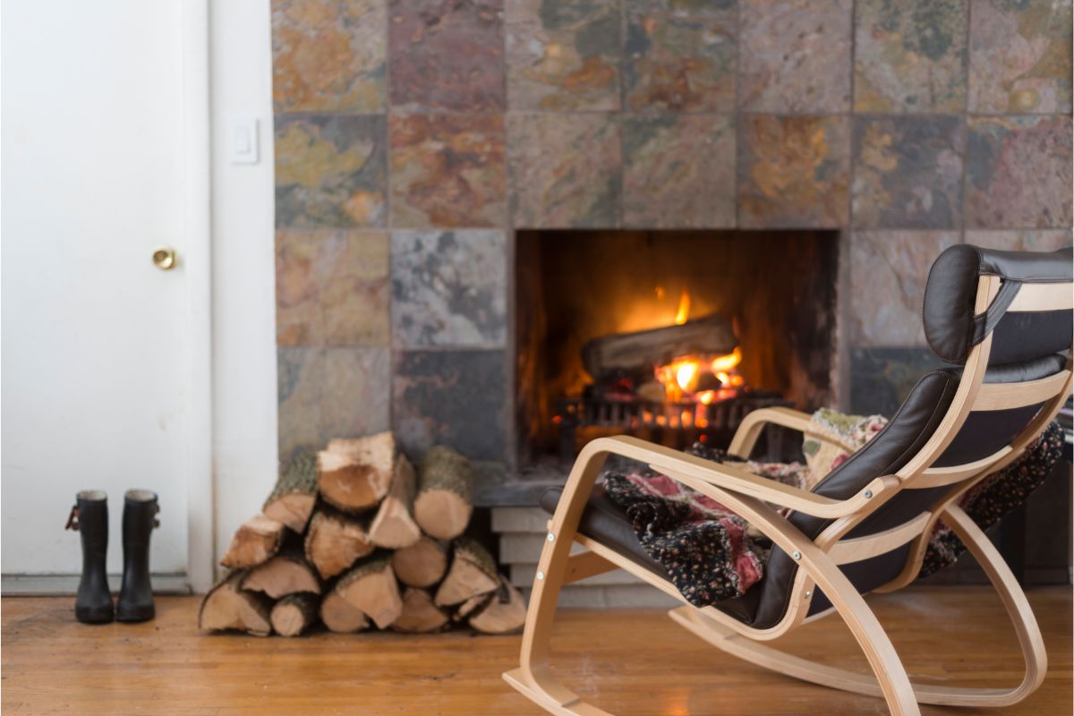 Wood logs in front of wood burning fireplace. Tiled fire surround and wood flooring.