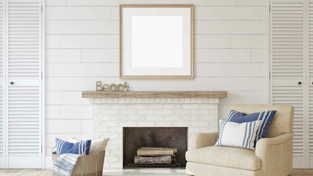 Fireplace in beach house with wood mantel. White brick fire surround. White tiled walls and mirror above fireplace.