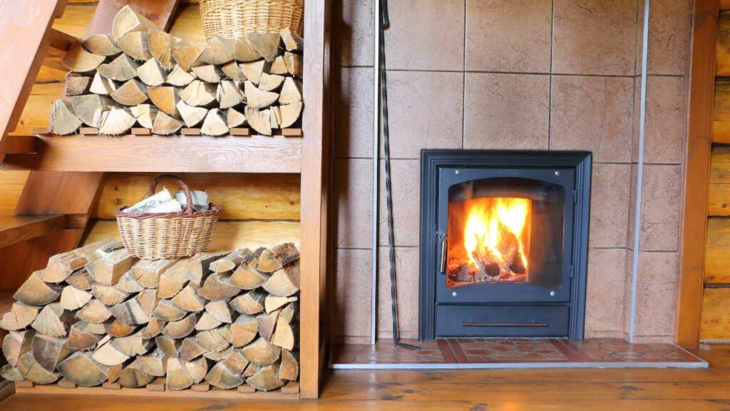 fireplace with brown rustic tiles set into the chimney breast. Wood storage stacked to one side.