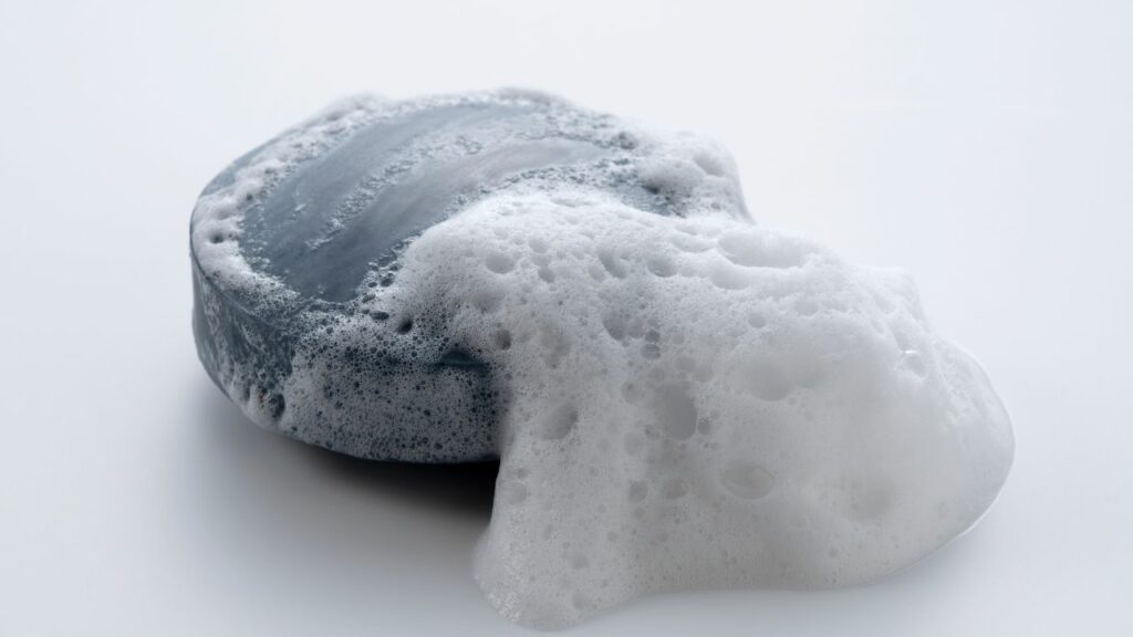 Light grey round soap bar with soap foam.