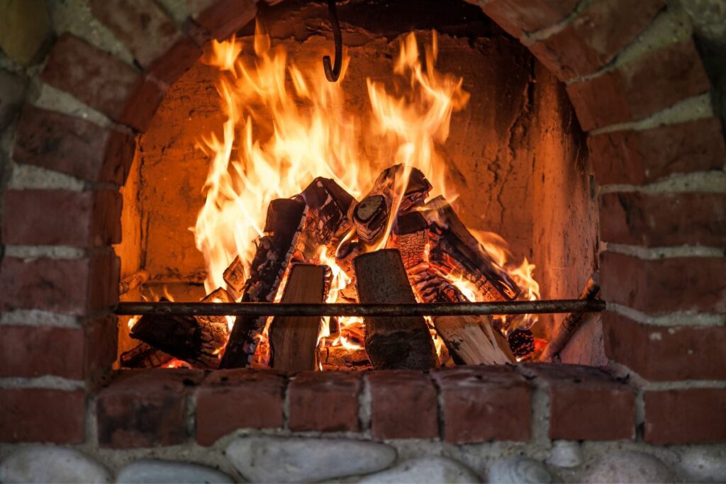 wood stacked and burning in a red brick fireplace.