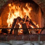 wood stacked and burning in a red brick fireplace.