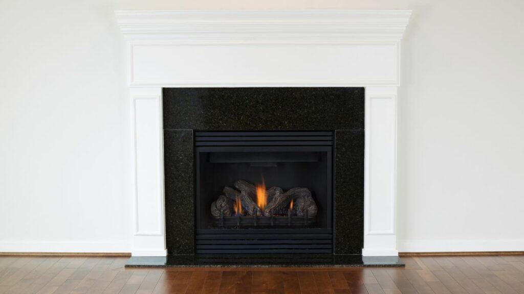 Vent free gas fireplace. fire burning. Wood flooring. White fireplace surround and white walls.
