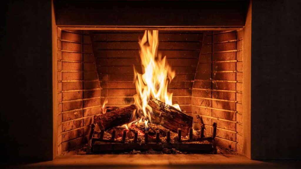 wood burning fireplace. Wood burning brightly. red brick fireplace surround.