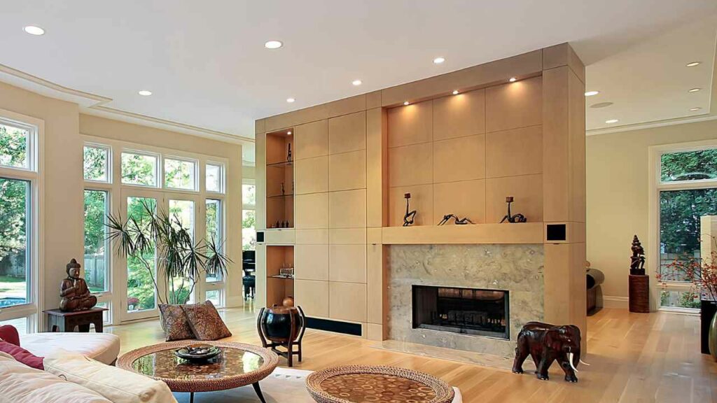 Subtle down lighting above fireplace. Marble surround. Wood flooring.