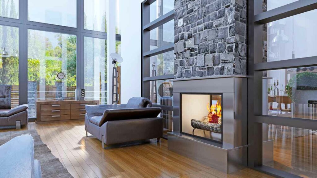 Industrial and modern living room. Steel fireplace with stone fireplace surround and chimney. wood flooring. very large windows.