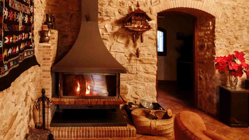 Meiteranean stone fireplace with brick hearth. wood burning. black patterned rug on the wall. morocan style.