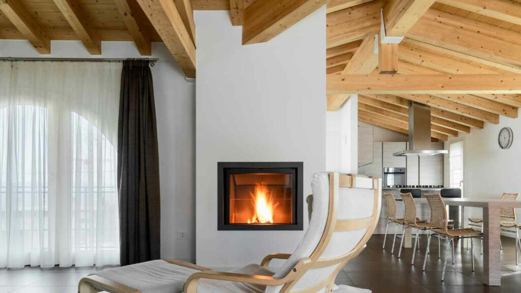 Minimalist zero clearance wood burning fireplace. white fireplace surround and flue. wood beams.
