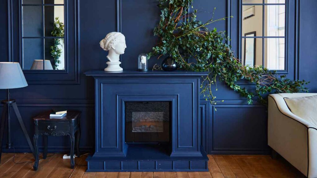 Navy painted fireplace. nave walls. plant on fireplace mantel. wood flooring.