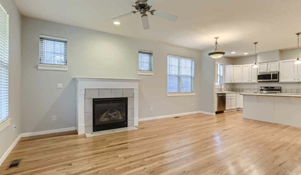 living room fireplace tile with wood flooring. Kitchen to one side.