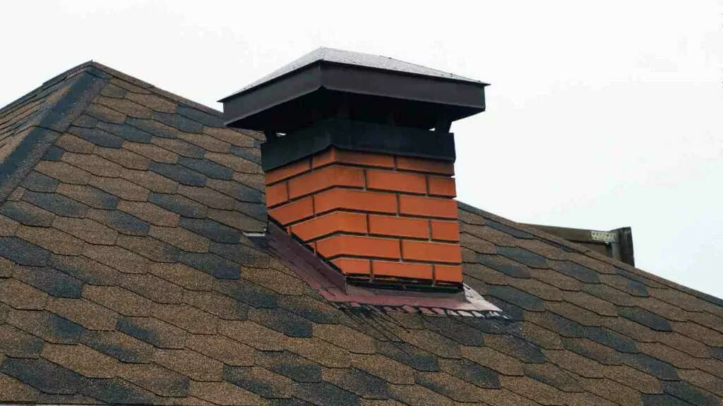 Red brick chimney with chimney cap. on roof.