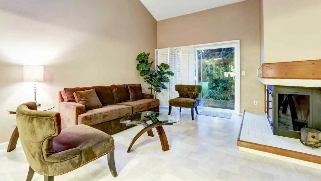 corner fireplace. joining two rooms. sofa in front of the fireplace. glass door to the backyard.
