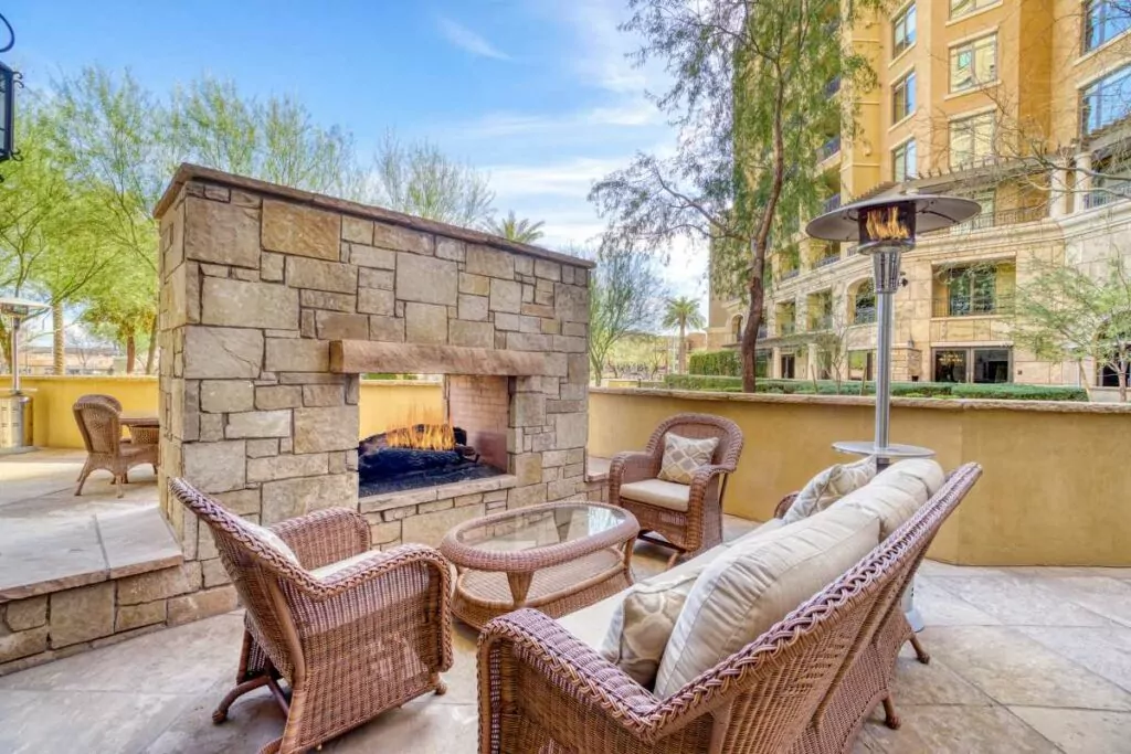 Stone vaneer outdoor fireplace dual sided with sofa chairs and glass table