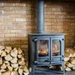 Red brick fireplace. Wood burning stove. Wood stacked either side.