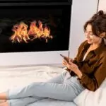 fireplace with woman n aophone keeping warm in front of the firepace.