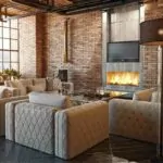 Fireplace in living room with sofa and TV above. Brick walls.