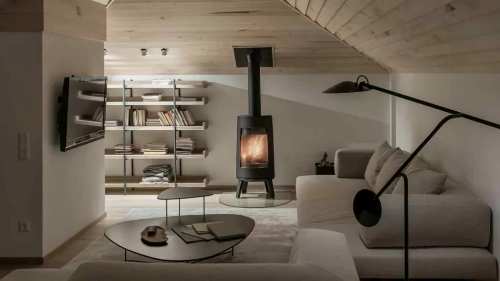 Modern wood burning fireplace with direct venting. Glass fronted fireplace with fire burning brightly. Wood walls and ceiling.