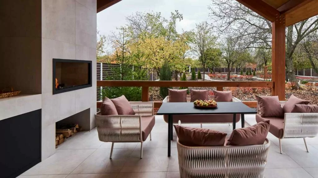 Outdoor fireplace in wall. Wood storage beloiw. Table and chairs in front.