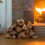 10 Fireplace Ideas that Will Make You Want to Live in a Scandinavian Cottage wood burning in a great in a fireplace. wood store to the side. pair of boots to the side. wood flooring.
