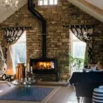 fireplace hearth, with black wood burning fireplace against stone wall.