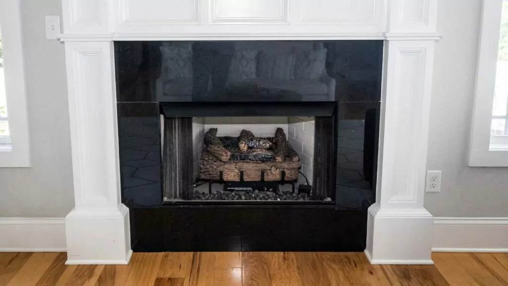 gas olg fireplace with black tile surround. wood flooring. white mantel.