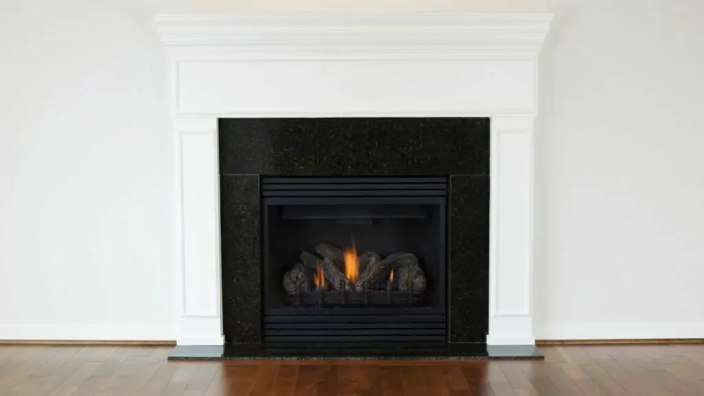 Vent free gas fireplace. fire burning. Wood flooring. White fireplace surround and white walls.